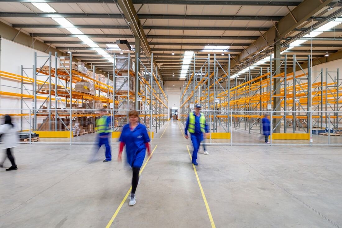Warehouse aisle with racked stock and staff at work